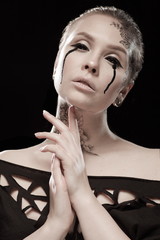 portrait of young brunette girl with black tears from eyes and lace pattern on face and neck posing...