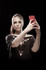 young brunette girl with black tears from her eyes makes selfie, talks and writes by phone