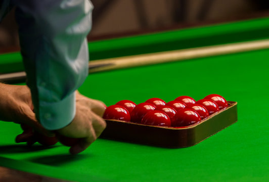 Snooker referee arranging red balls at the beginning of a game