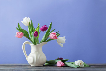 tulips in jug on violet background