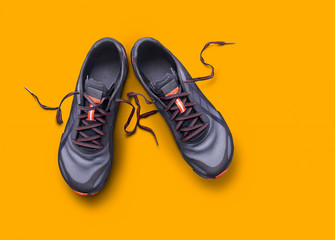 Top view of gray and orange trainers isolated on a yellow background.