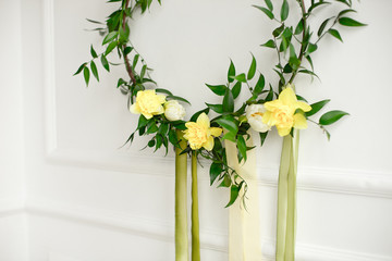 Close-up green wreath of narcissus and plants on the white wall