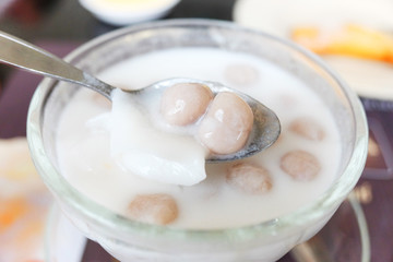 Fototapeta na wymiar Thai dessert. Taro Pearls in Coconut Milk. Taro Balls in Sweet Coconut Cream in glass bowl - Bua Loey