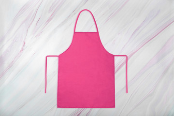 Pink apron on marble background with natural pattern. Flat lay. Top view