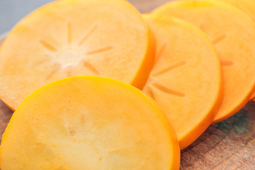 Naklejka na ściany i meble close up of orange cut persimmons slices on wooden board