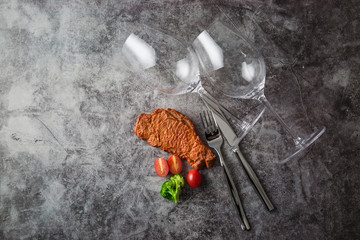 Fork, knife,beef steak and glasses on table. Dishware