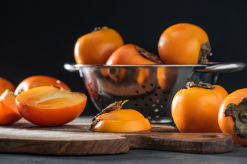 selective focus of orange persimmons on cutting board and in colander