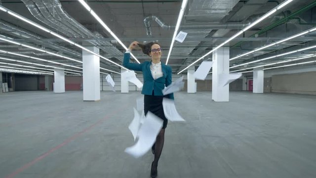 Female office manager is walking along the hall and starts fooling around