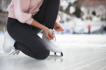 Woman tie shoelaces figure skates at ice rink close-up