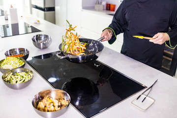 Chef cooking fresh vegetables  on a wok