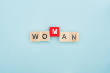 top view of woman lettering made of wooden blocks on blue background