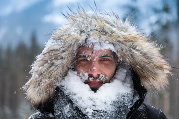 Man's face covered with snow against the backdrop of winter mountains