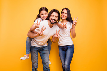 Fototapeta premium Portrait of nice cute sweet lovely attractive charming cheerful dreamy funny people mom dad pre-teen girl showing v-sign isolated over shine vivid pastel yellow background