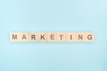 top view of marketing lettering made of wooden cubes on blue background