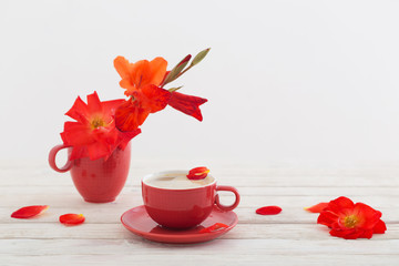 cup of coffee with red flowers on white wooden table
