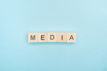 top view of media lettering made of wooden cubes on blue background