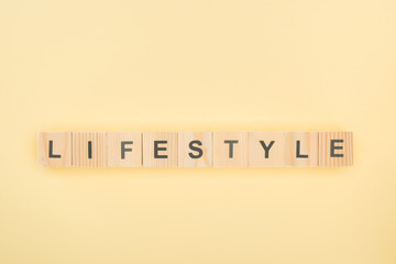 top view of lifestyle lettering made of wooden cubes on yellow background