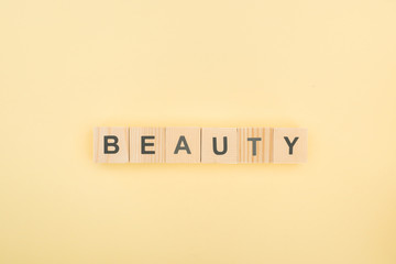 top view of beauty lettering made of wooden cubes on yellow background