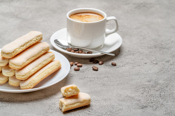 Italian Savoiardi ladyfingers Biscuits and cup of coffee on concrete backgound