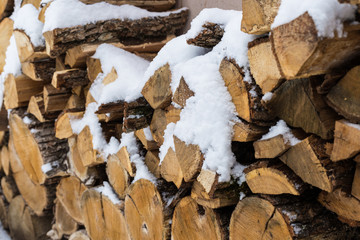 Chopped stock of firewood under snow on the street. Firewood for fireplace and bbq