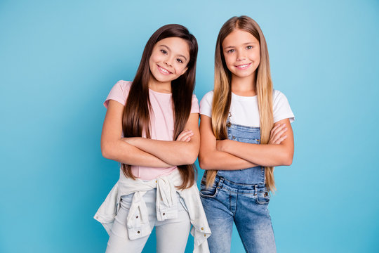 Portrait of nice-looking cute lovely sweet adorable well-groomed attractive cheerful cheery straight-haired brunette blonde girls siblings folded arms isolated over blue pastel background