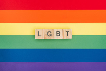 top view of lgbt lettering made of wooden blocks on paper rainbow background