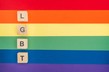 top view of lgbt lettering made of wooden cubes on paper rainbow background