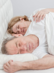 Fototapeta na wymiar Happy elderly couple sleeping together on the bed
