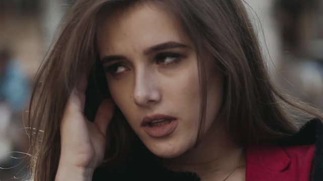 Pretty woman tolerates headache on a street among passers-by
