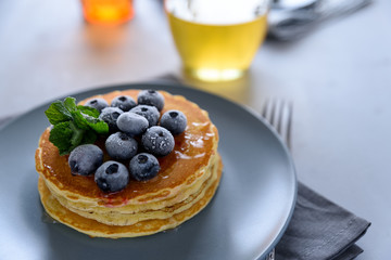 Stack of pancakes with frozen blueberry and honey on gray background. Selective focus