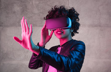 Cute black teenager exploring virtual reality near concrete wall