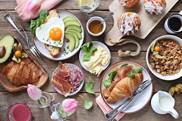 Breakfast food table. Festive brunch set, meal variety with fried egg, croissant sandwich, granola and smoothie. Overhead view