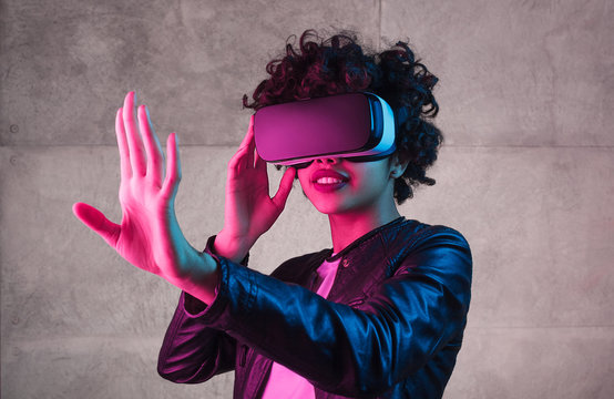 Cute black teenager exploring virtual reality near concrete wall