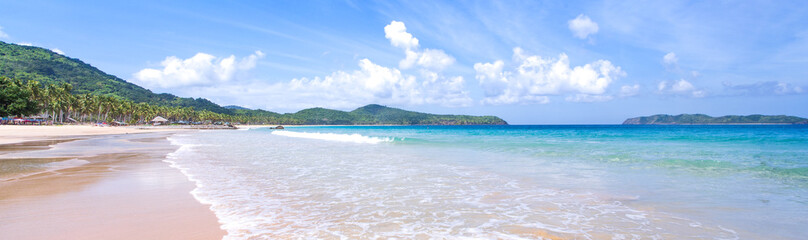 Beautiful amazing gold colored sandy beach with soft waves isolated with sunny blue sky. Concept of tropical calm tourism idea, copy space, close up