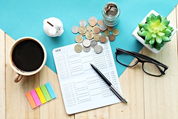 Business, finance, saving money, investment or accounting concept :  Top view or flat lay of piggy bank, saving account book or financial statement and coins on office desk table