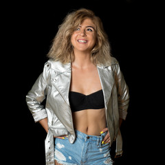 Beautiful and sexy blonde posing on a black background. The model smiles widely. Studio photo.