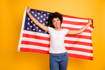 Close up photo beautiful amazing she her dark skin lady hands arms hold american flag festive mood 4th of july wearing casual jeans denim white t-shirt isolated yellow bright vibrant background
