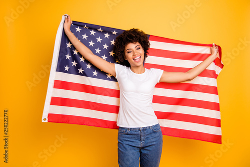 Close up photo beautiful amazing she her dark skin lady hands arms hold american flag festive mood 4th of july wearing casual jeans denim white t-shirt isolated yellow bright vibrant background