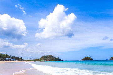 Beautiful amazing gold colored sandy beach with soft waves isolated with sunny blue sky. Concept of tropical calm tourism idea, copy space, close up