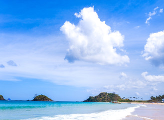 Beautiful amazing gold colored sandy beach with soft waves isolated with sunny blue sky. Concept of tropical calm tourism idea, copy space, close up