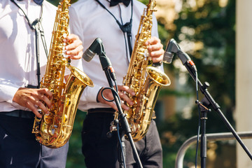 two saxophonists playing at a jazz festival in a city park