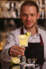 Margarita alcohol cocktail with lime ice. Alcohol cocktail on black background surface.  Barmen is making Margarita