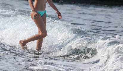 Fototapeta premium Girl in a swimsuit on the beach of the sea