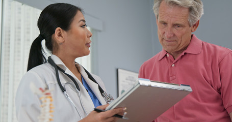Female primary care physician taking medical history from senior Caucasian male patient. Japanese...