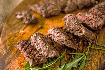 Beef Machete Steak. Grilled steak on a wooden board on a dark background. Delicious grilled meat, medium steak grilled, roast beef pieces.  Machete steaks of medium roast on a wooden board