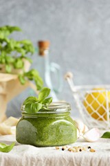 Pesto.Traditional italian basil pesto sauce in glass jar over rustic wooden table. 