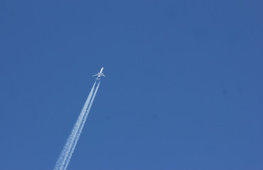 Twin-engined airplane with contrails entering in picture from the left.