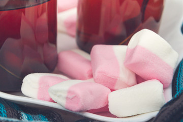 White-pink marshmallow on a plate with two cups of tea