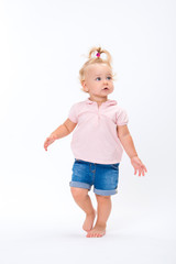Cute little child baby girl learns to walk, make first steps isolated on a white background