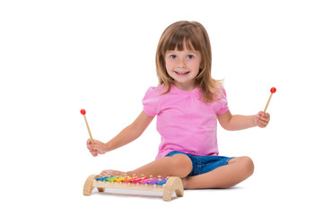 Cute smiling cheerful positive girl 3 years old playing with musical instrument toy xylophone isolated on white background